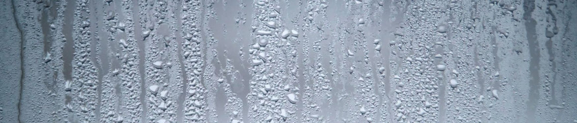 Close-up of water stains and mineral buildup on shower glass.